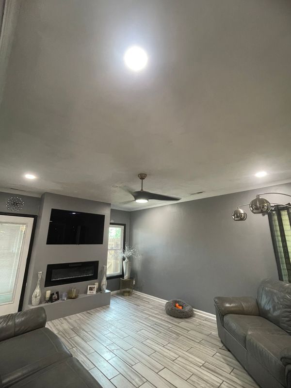 Living room with gray walls, fireplace, TV, ceiling fan, and hardwood floor.