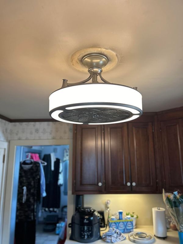 Ceiling-mounted light fixture in kitchen with dark cabinets and a door leading to a closet with clothes.