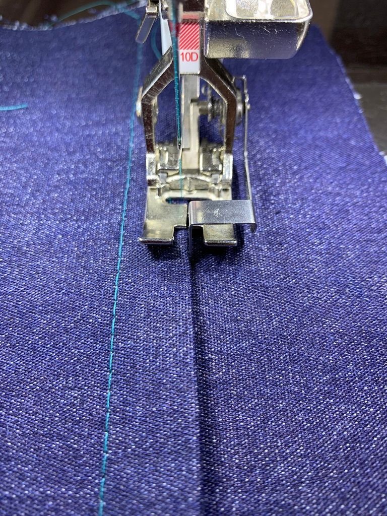 Sewing machine foot stitching denim fabric.