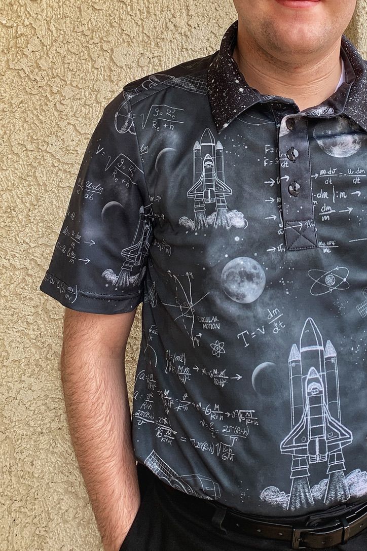 Man wearing a space-themed polo shirt, standing in front of a textured beige wall.