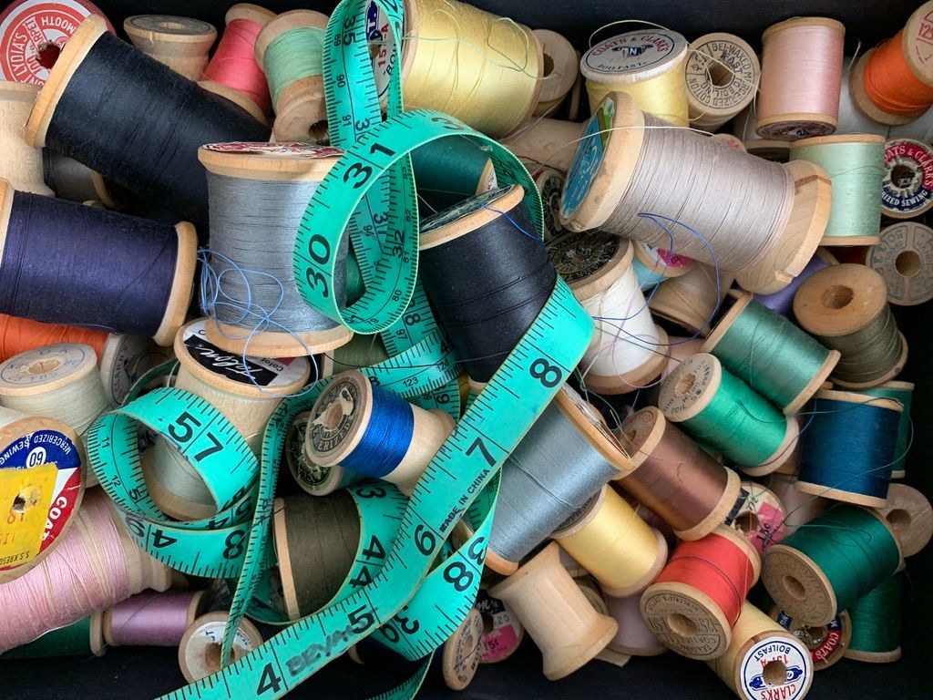 Spools of colorful thread and a green measuring tape in a pile.