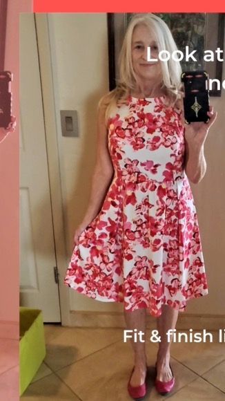 Woman in a floral red and white dress, holding phone, in a brightly lit room.