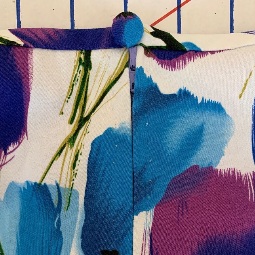 Close-up of fabric with a button closure; blue, purple, and green floral design.