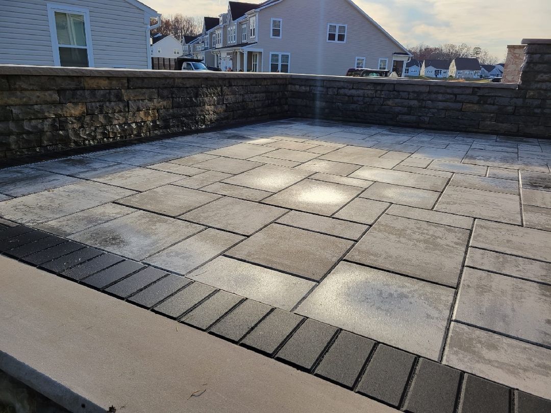 A patio with a brick wall and a house in the background.