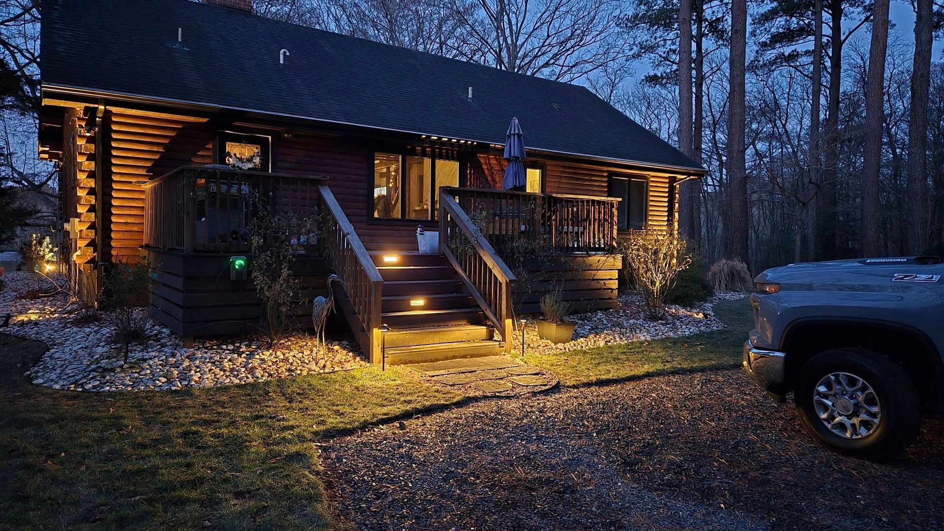 A truck is parked in front of a log cabin at night.