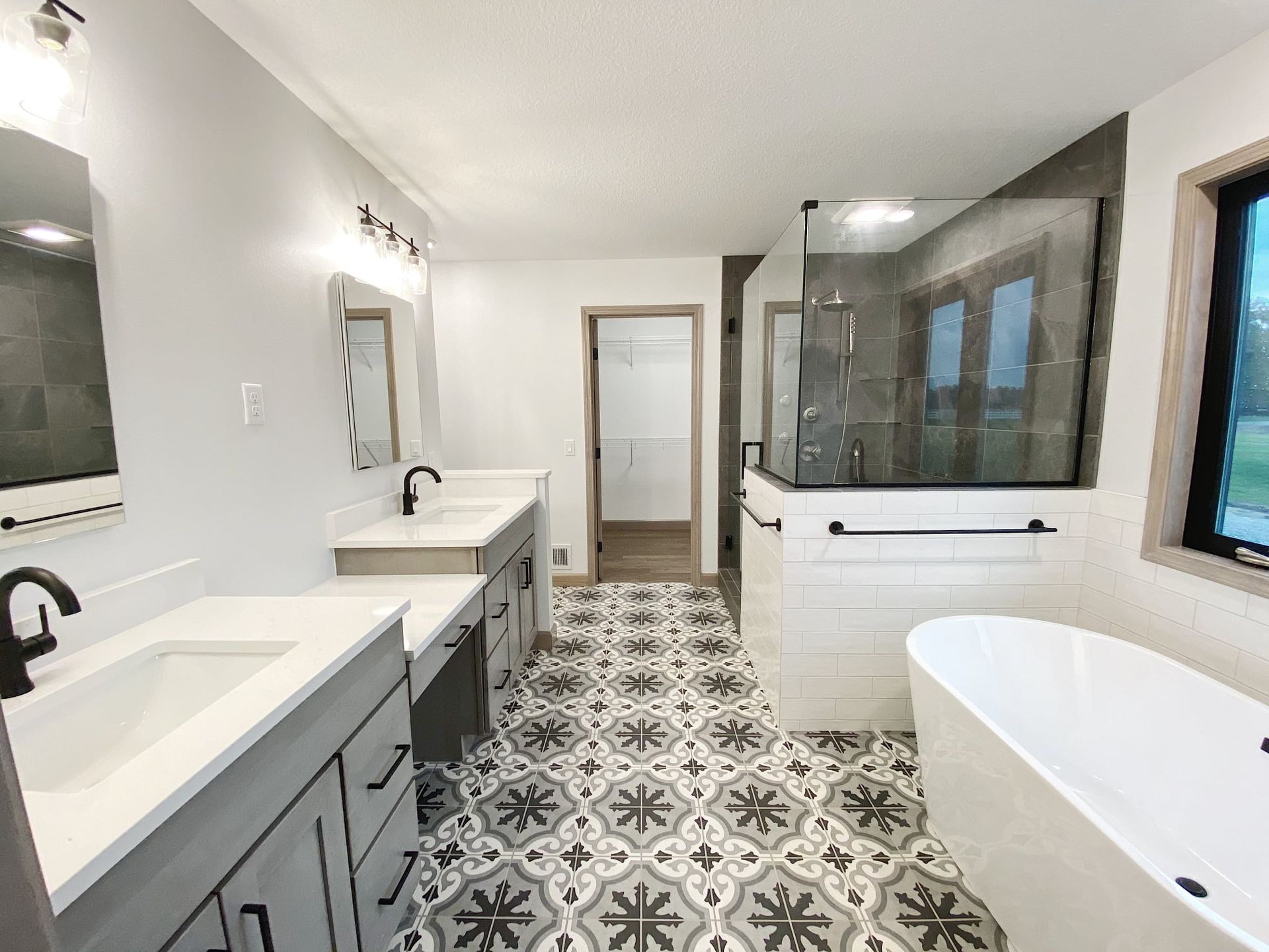 Modern bathroom with double vanity, freestanding tub, patterned tile floor, and walk-in shower