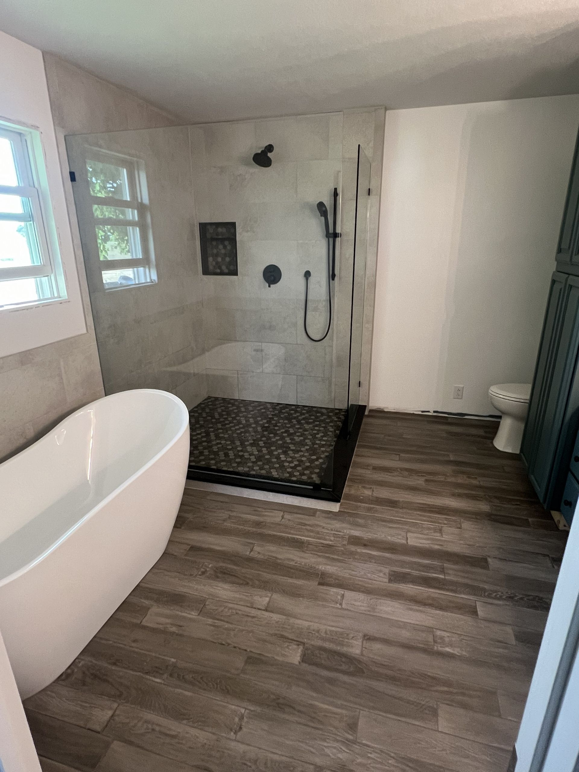 Bathroom with freestanding tub, walk-in shower, toilet, and wood-look flooring