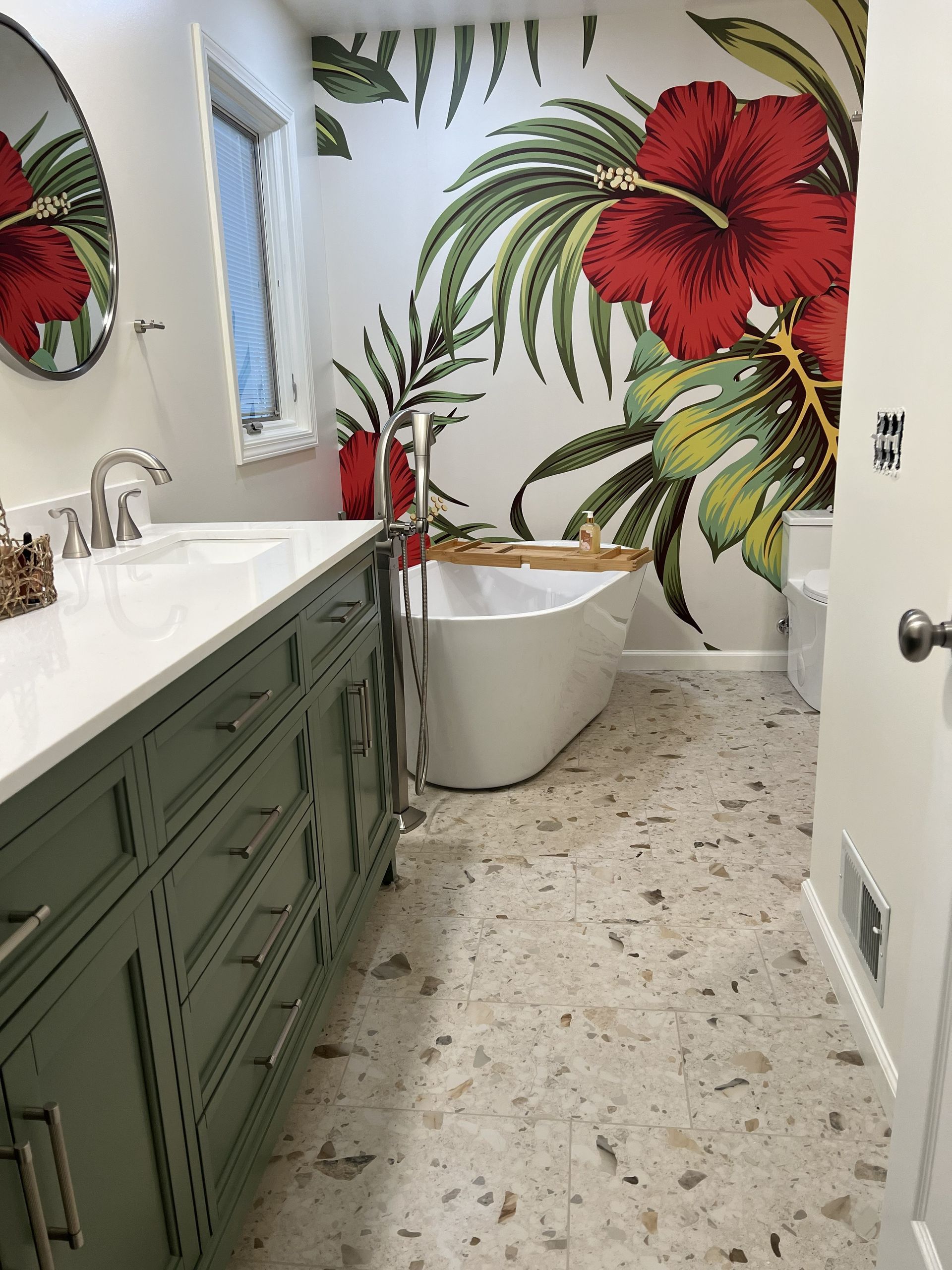 Bathroom with green vanity, white tub, and large red flower mural on the wall.
