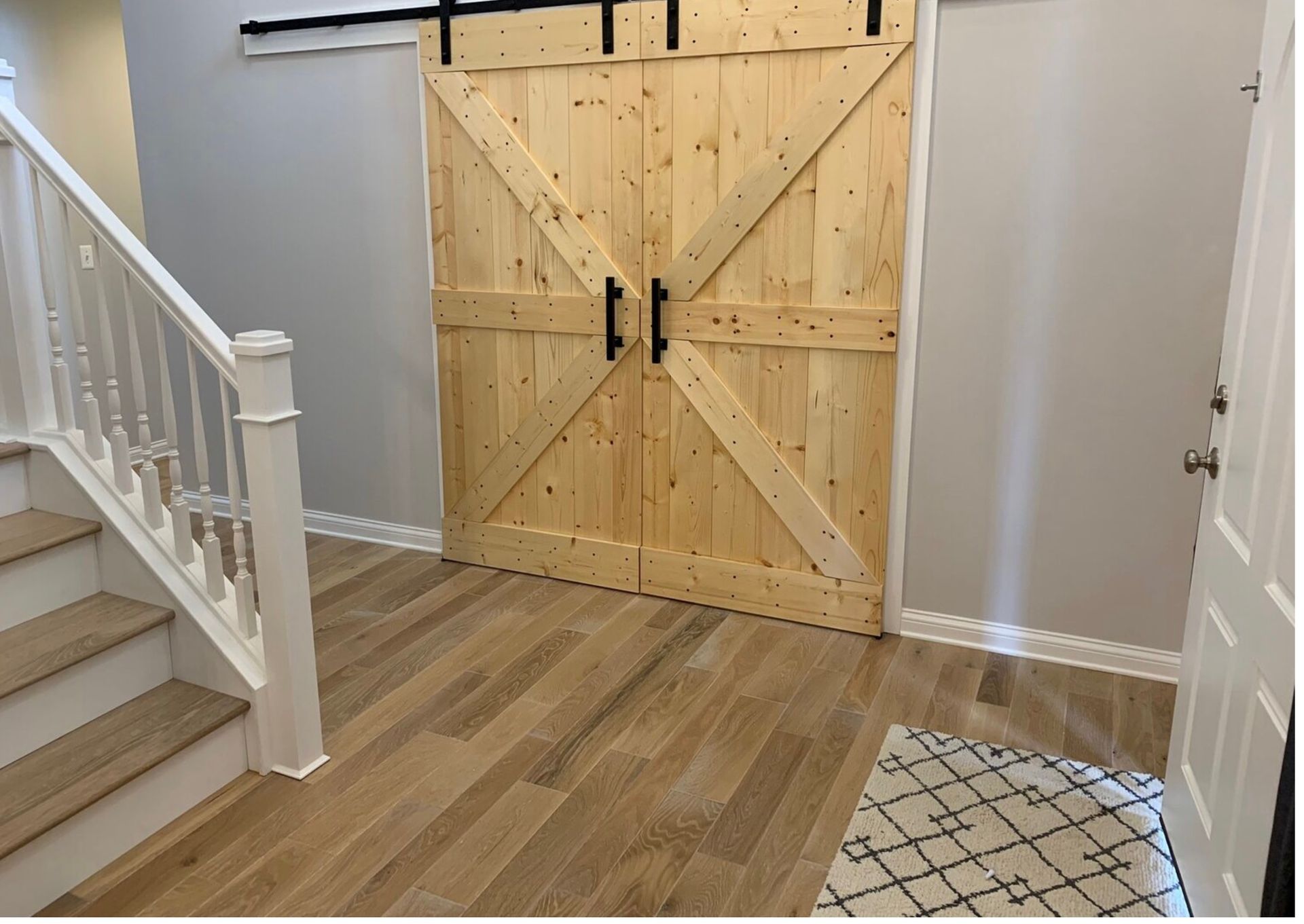 Interior hallway with a large wooden barn door and staircase on the left.