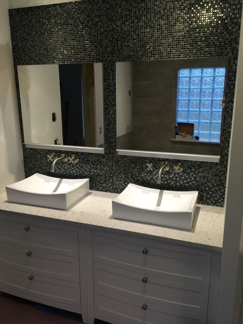 Modern bathroom vanity with double sinks, mirrors, and dark mosaic tile backsplash