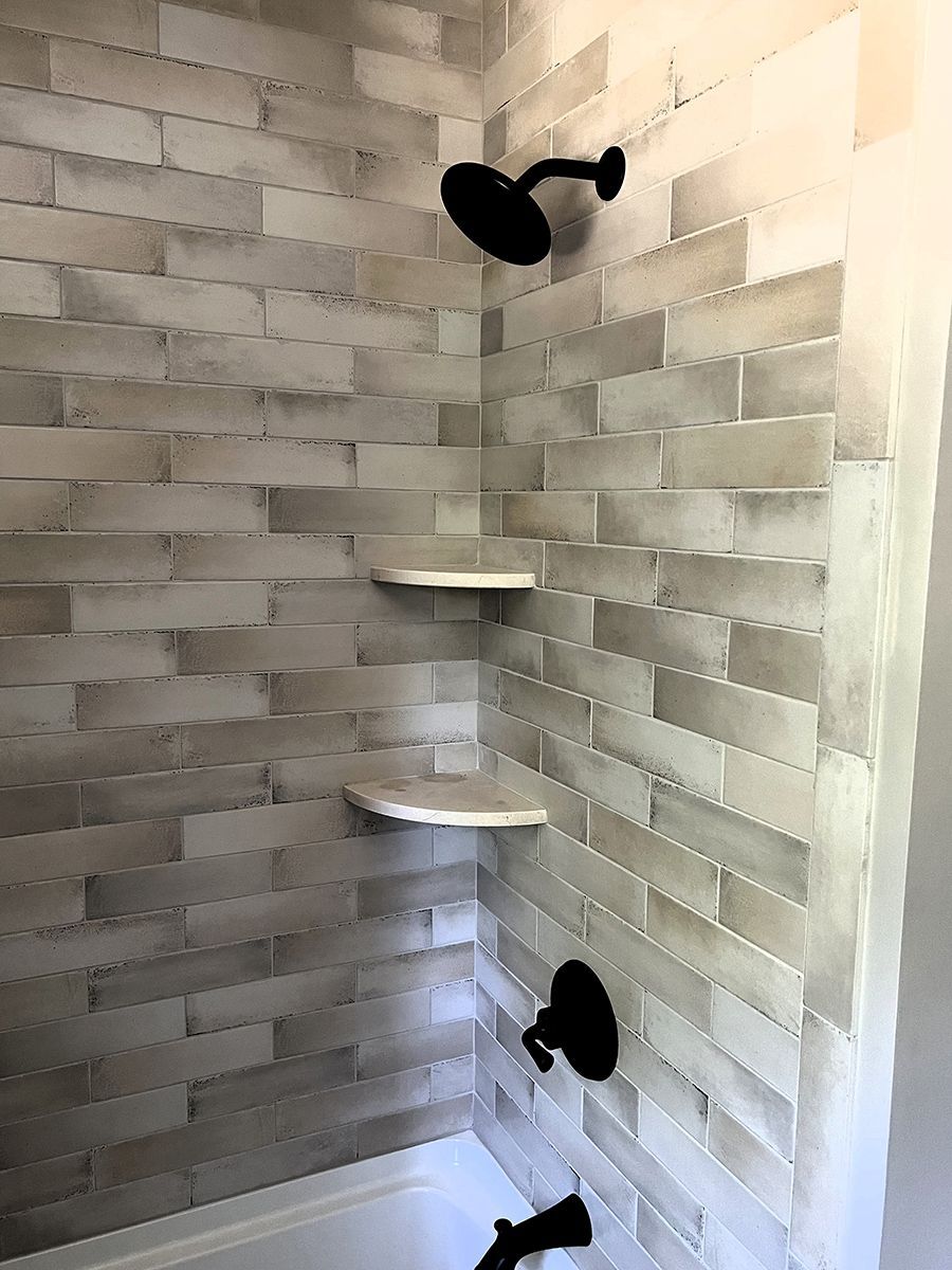 Corner shower with gray tile, two corner shelves, and black showerheads on opposite walls