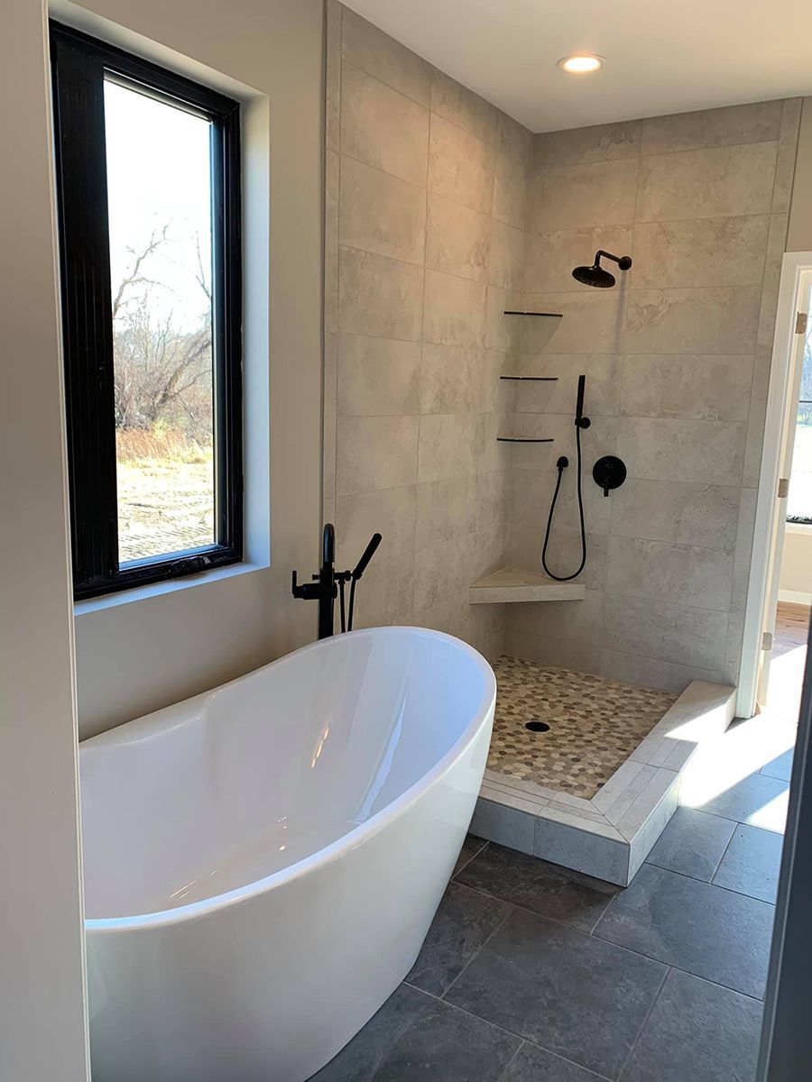 Modern bathroom with a freestanding tub, tiled walk-in shower, and black-framed window light.
