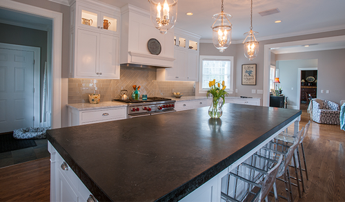 Modern kitchen with large dark island, white cabinets, pendant lights, and stainless-steel appliances