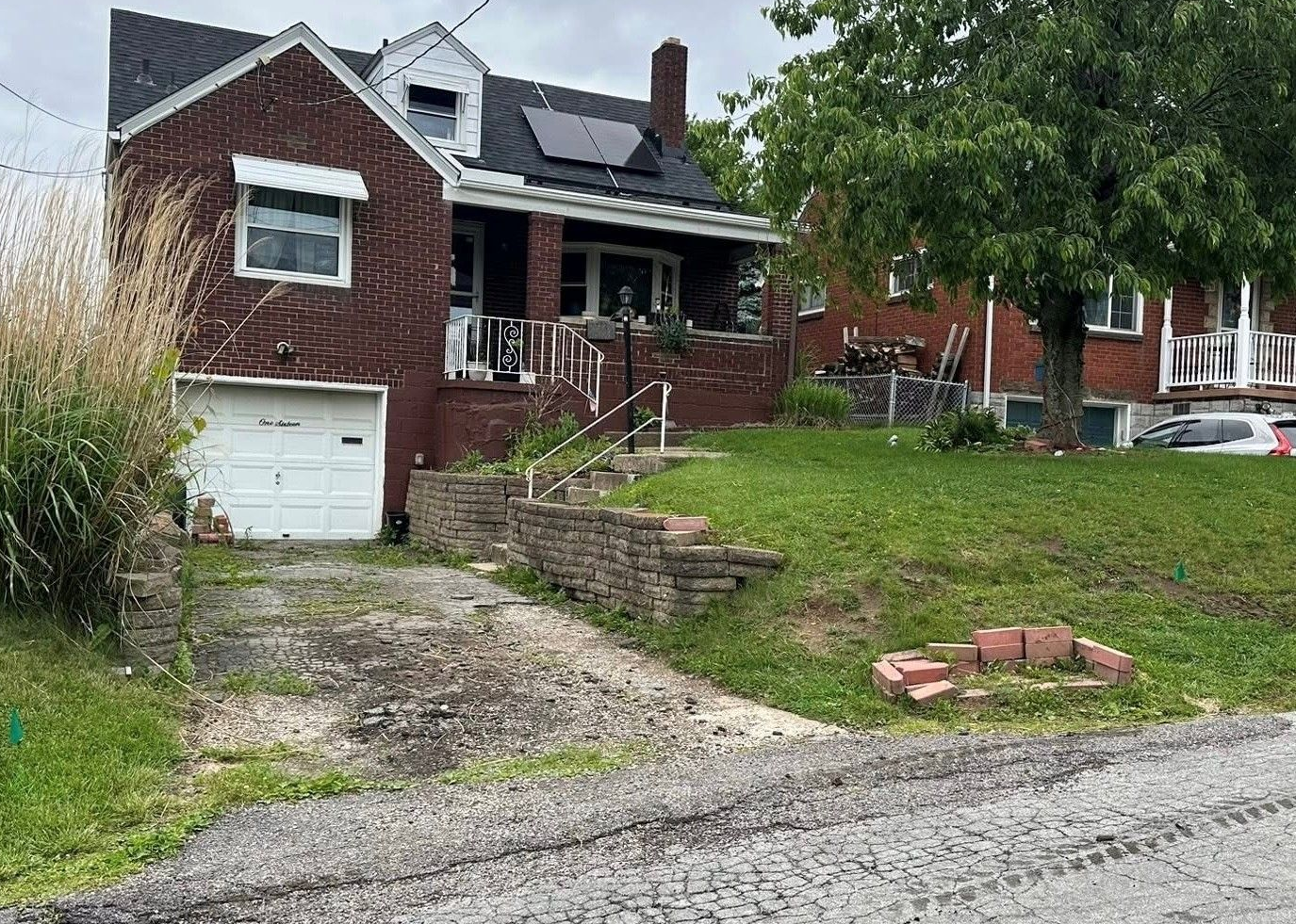 Brick house with garage, front porch, and sloped lawn
