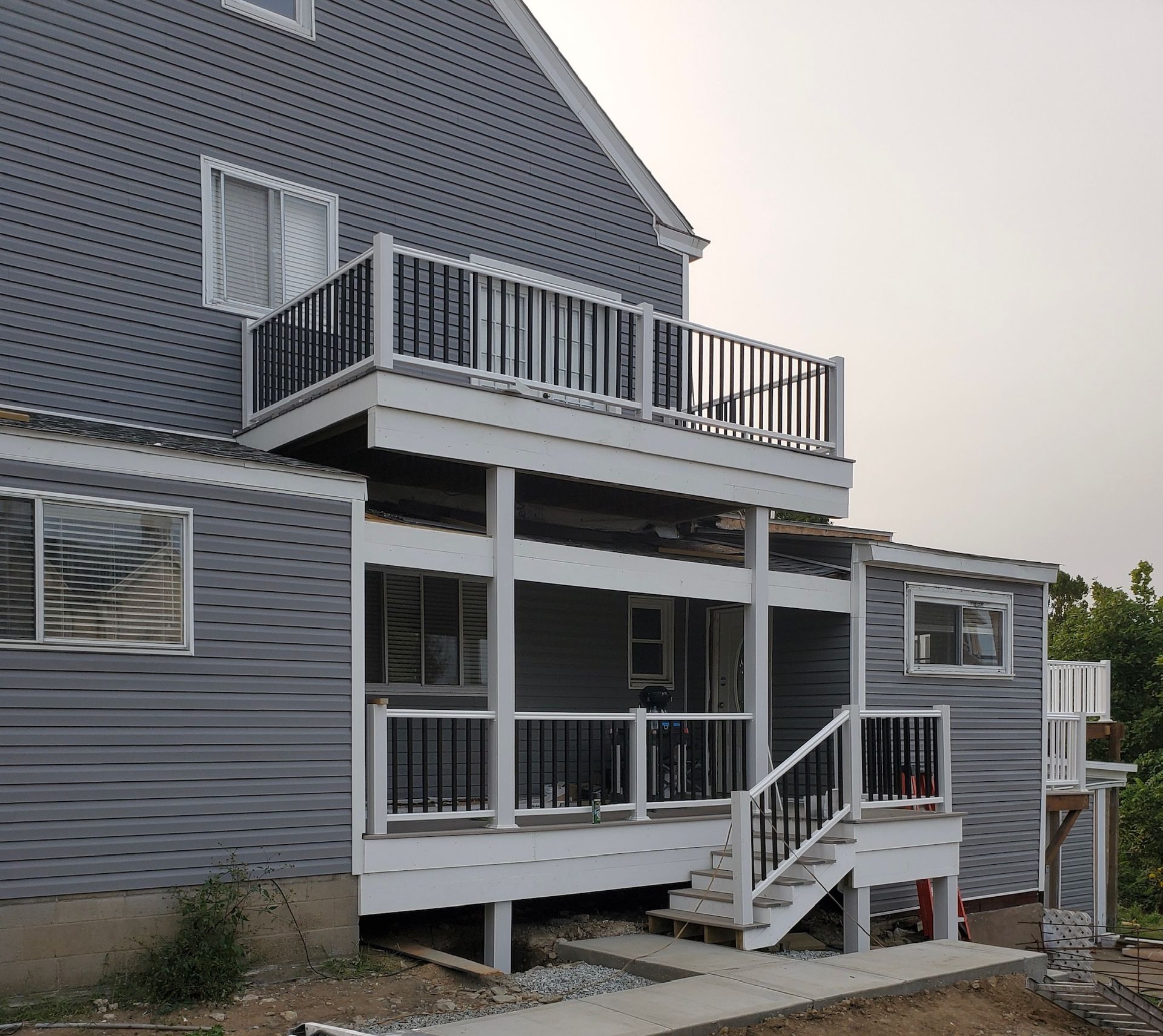 Gray house exterior with multi-level deck, stairs, and balcony at dusk