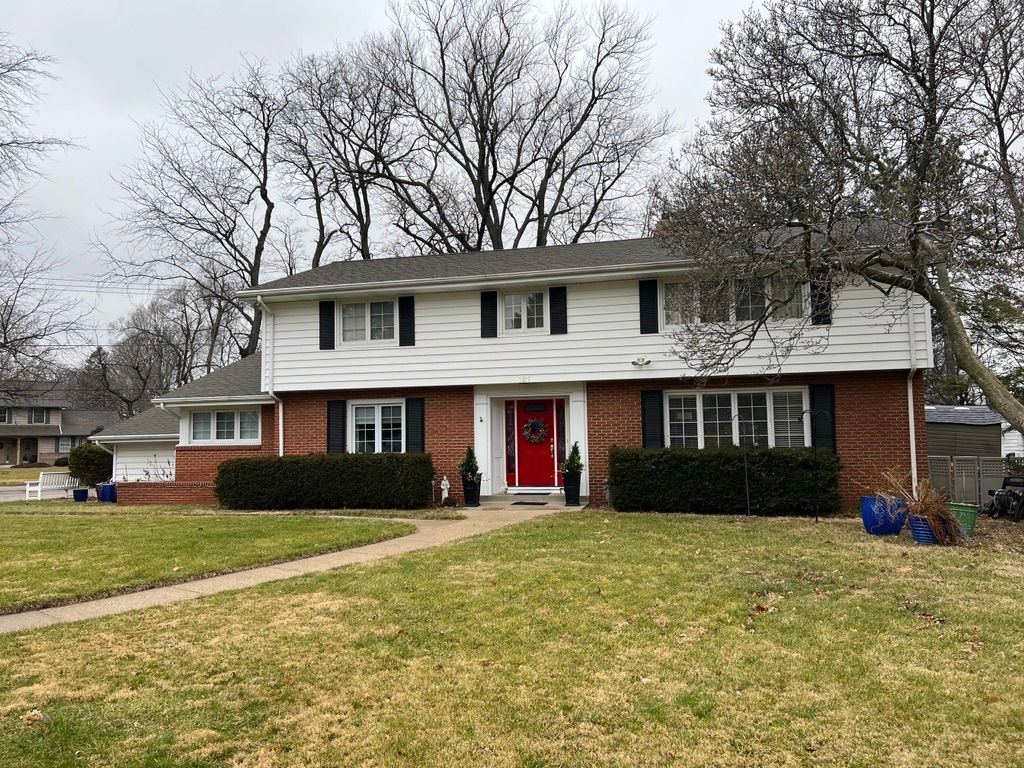 A large brick house with a red door and black shutters.