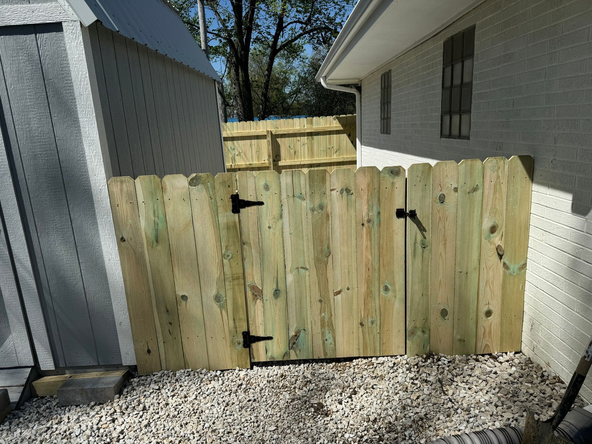A wooden fence with a gate is in front of a white house.