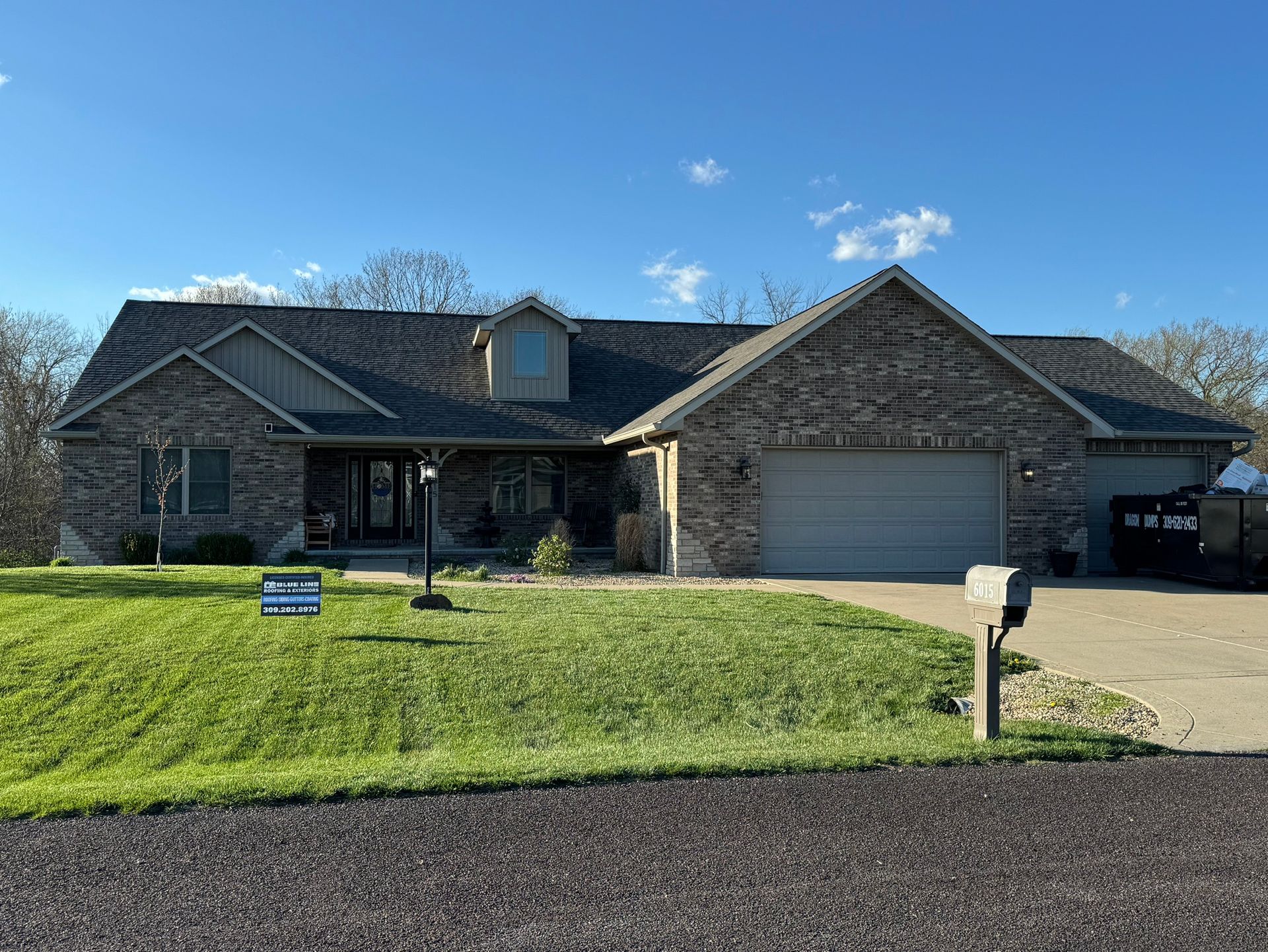 A large brick house with a large garage and a sign in front of it.