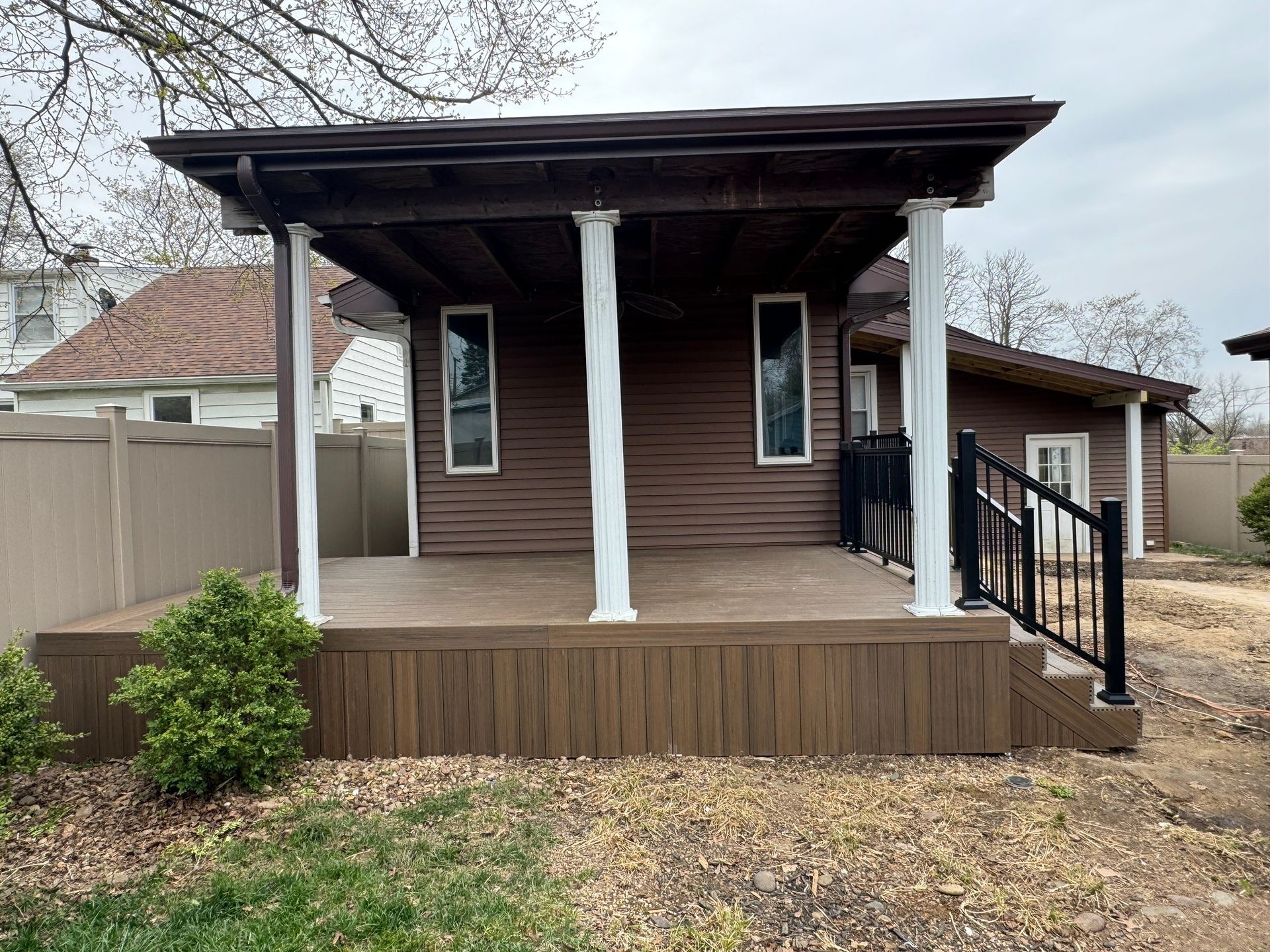A small house with a porch and a fence in the backyard.