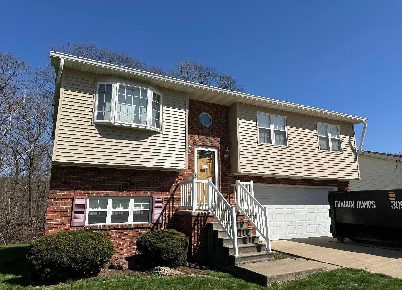 A large brick house with a white garage door and stairs.