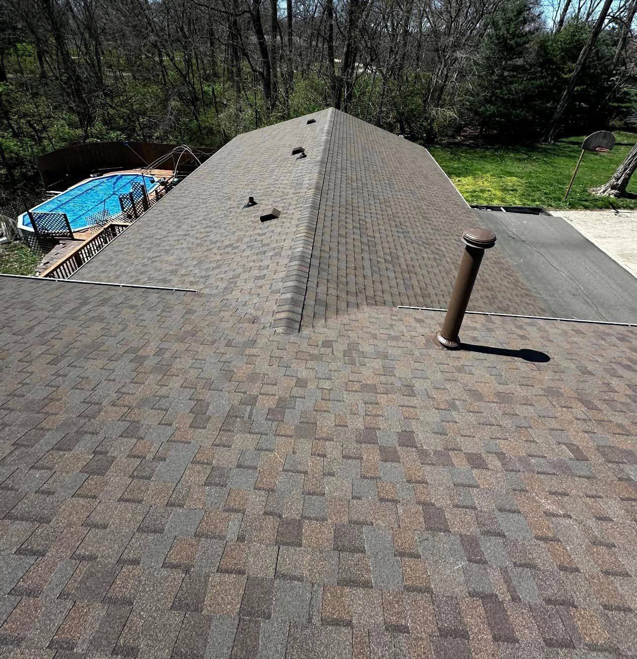 The roof of a house with a swimming pool in the background.