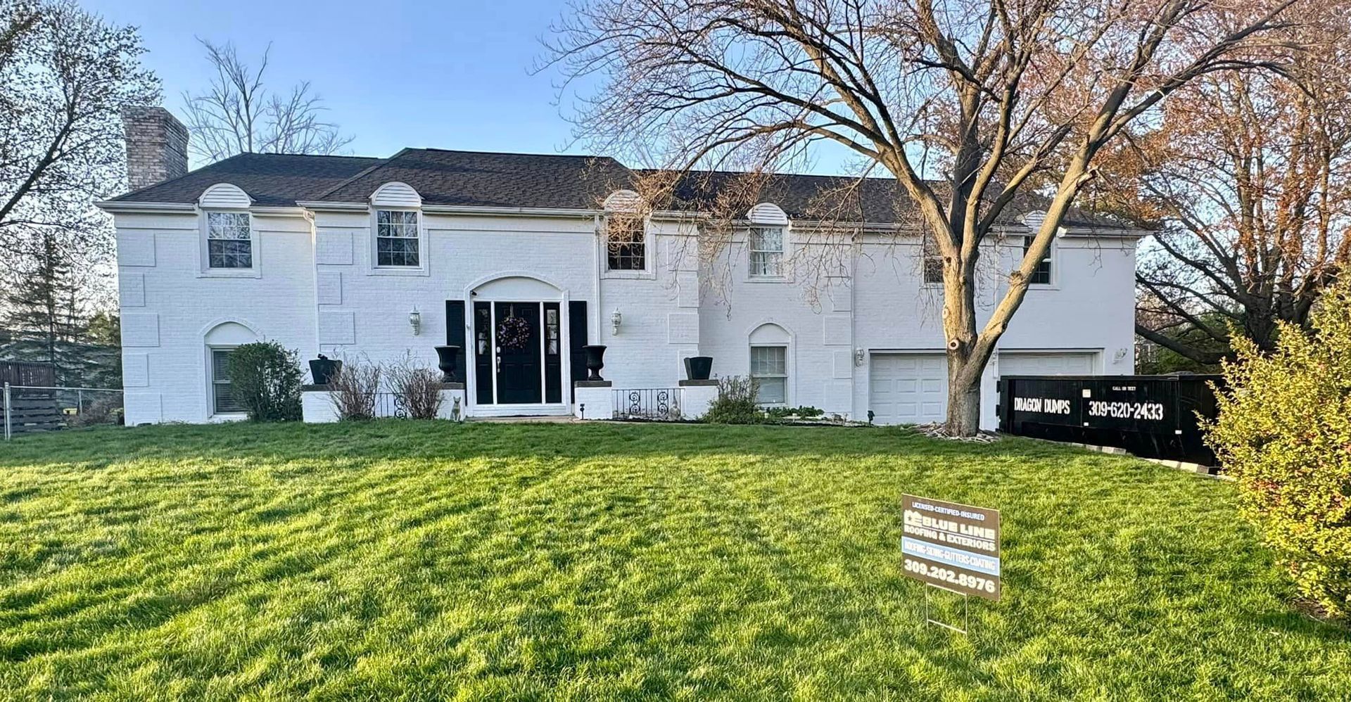 A large white house with a lush green lawn in front of it.