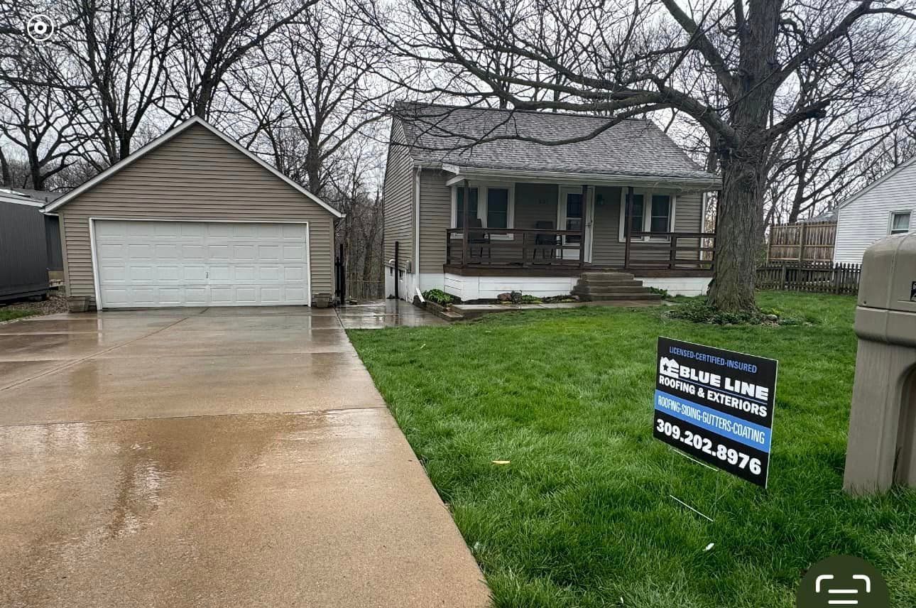A house with a garage and a for sale sign in front of it.