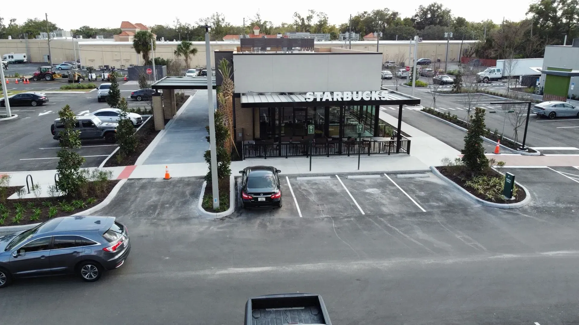 Starbucks building with drive-thru, surrounded by parking lot and cars on an overcast day.