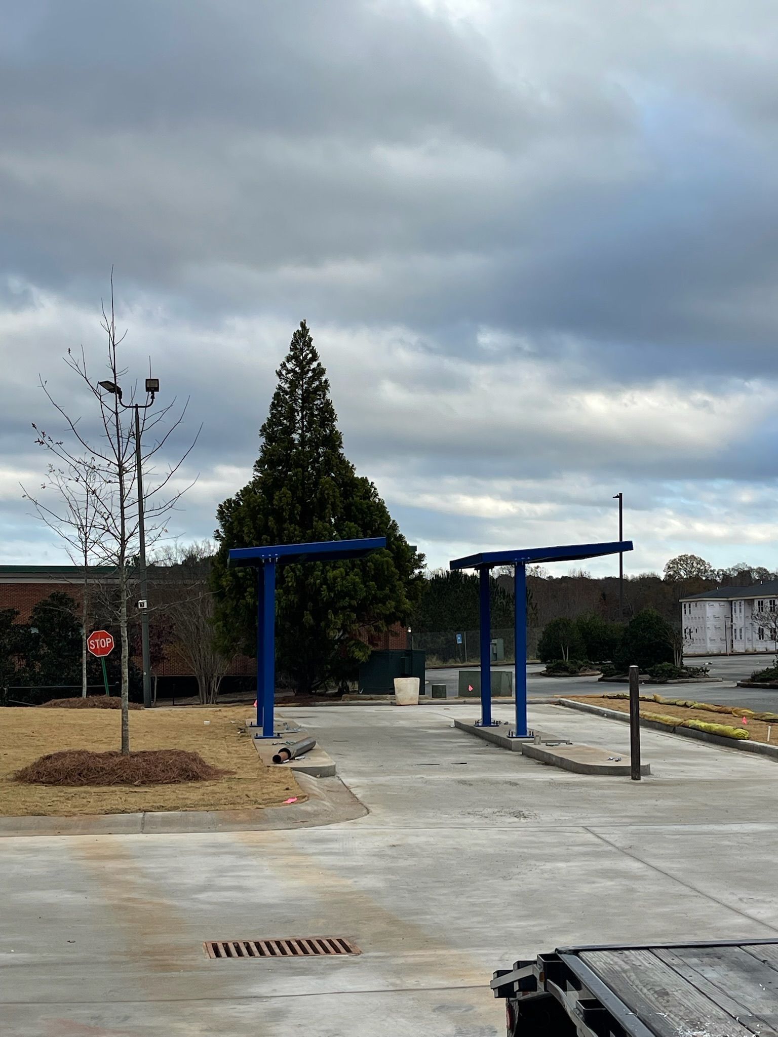 Blue car wash canopy structure under a cloudy sky.
