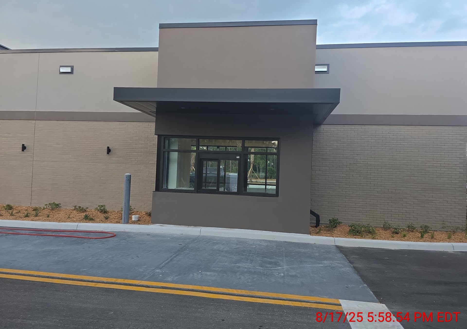 Drive-up window under a dark gray awning on a tan building with a textured wall.