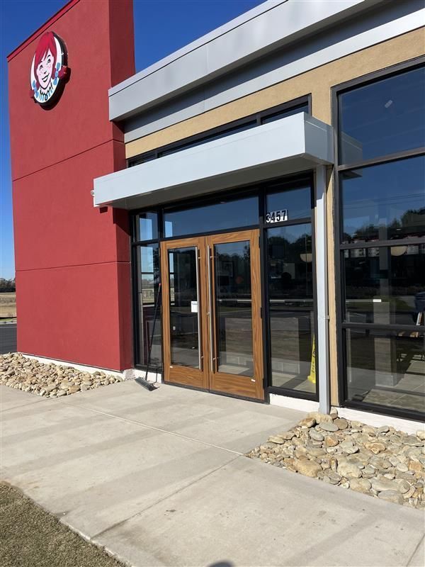 Exterior of Wendy's restaurant with red facade, double doors, and sidewalk.