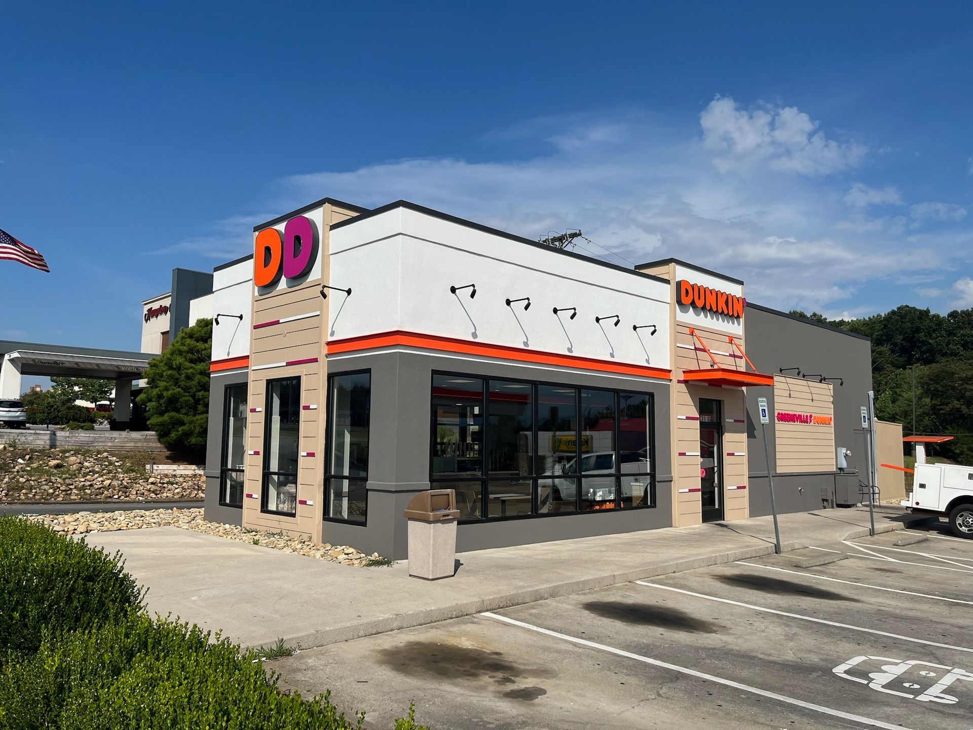 Dunkin' Donuts storefront with orange and white sign against a blue sky.