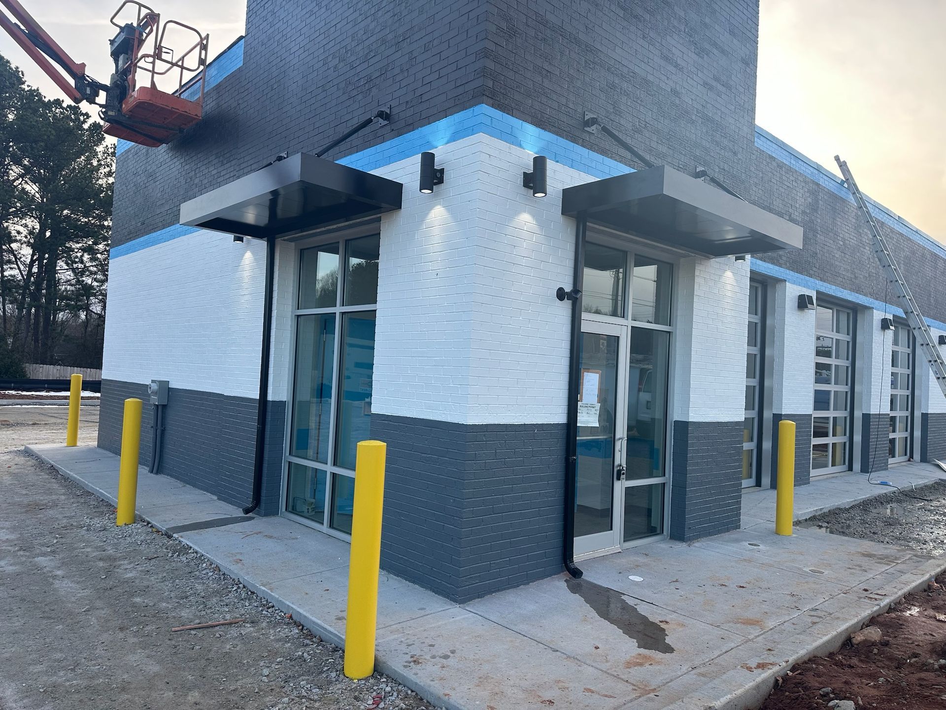 Exterior of a commercial building with white and gray brick, blue accents, and a black awning.