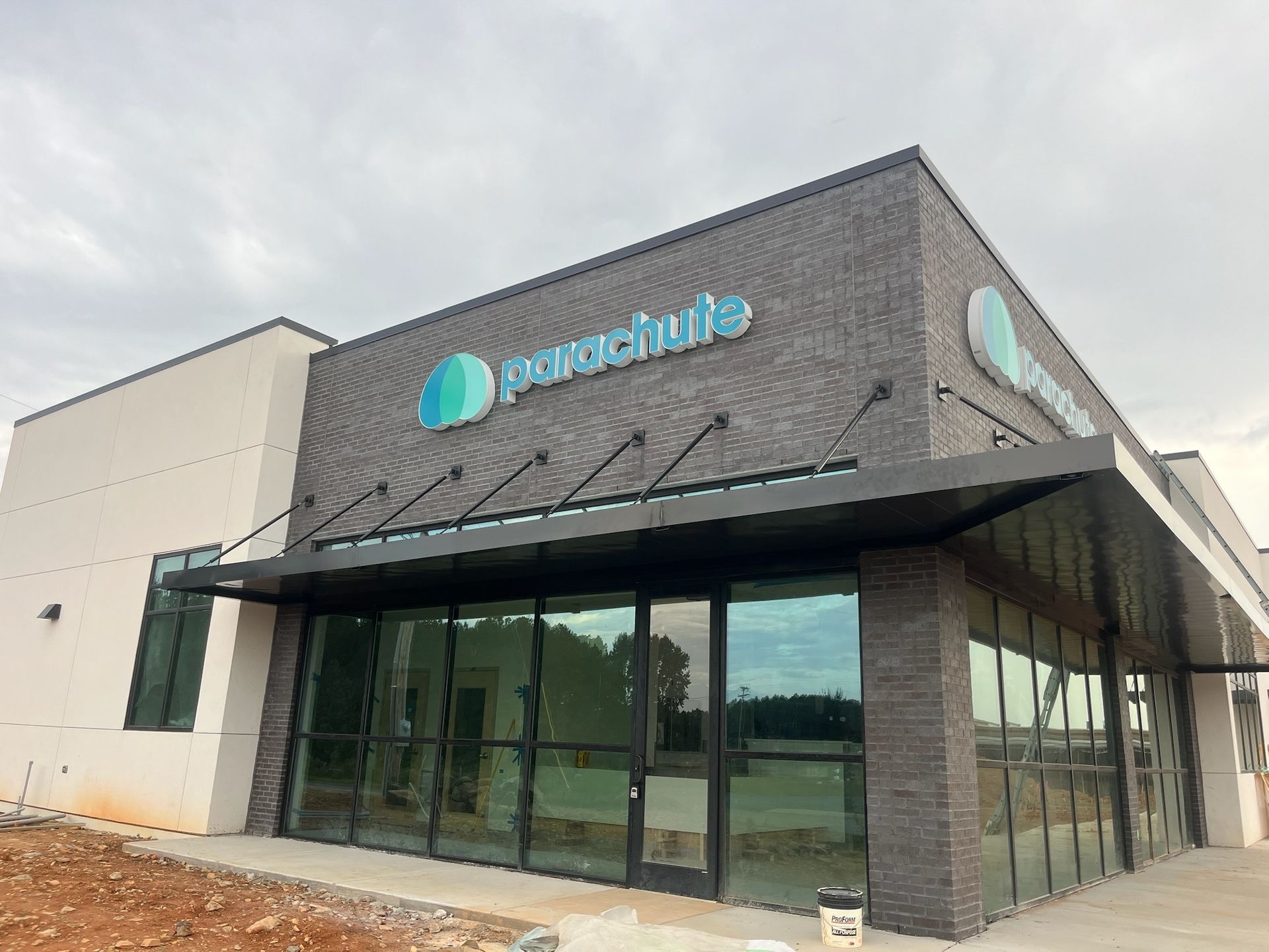 Parachute store exterior with large windows, dark brick, and blue logo.