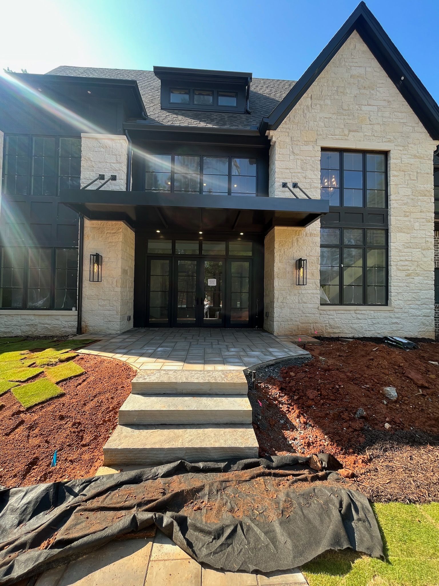 Beige stone home entrance with black trim, windows, and awning. Stone steps lead to the front door.