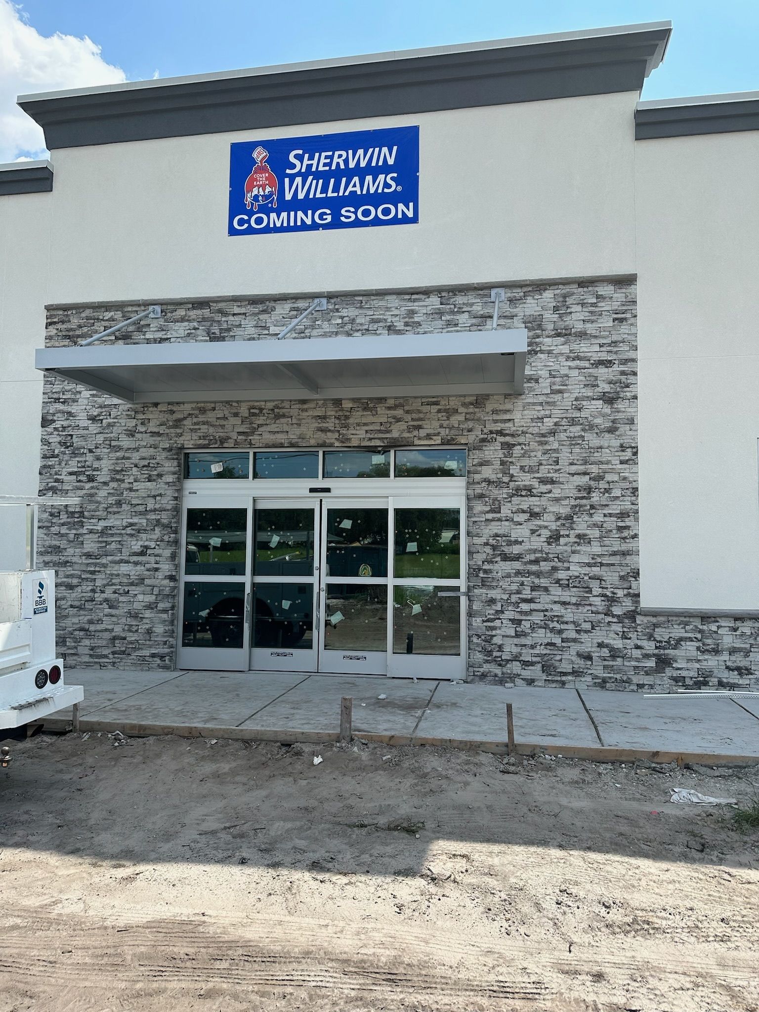 Sherwin-Williams store under construction; entrance with automatic doors, stone facade, and 