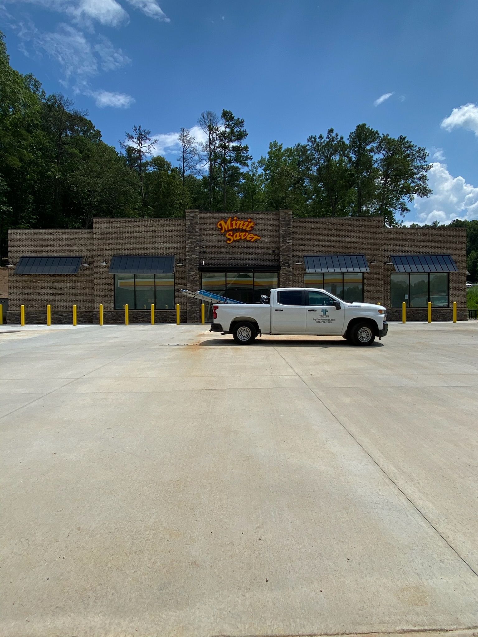 White pickup truck parked in front of a brick building with a sign that says 