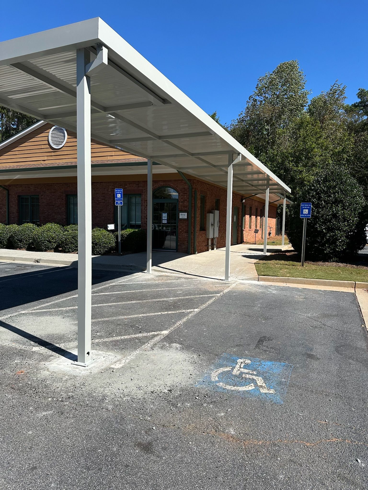 Parking lot with a covered walkway leading to a brick building. Two handicap parking signs.