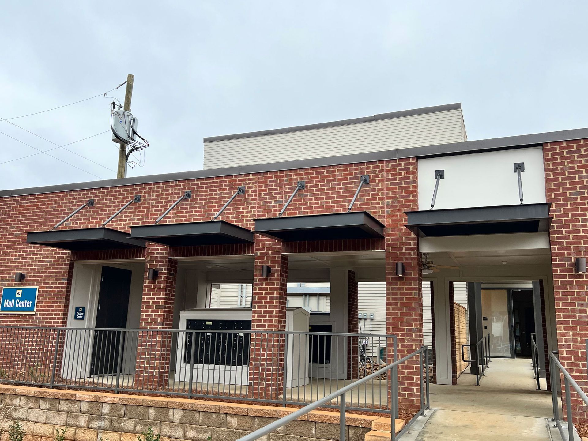 Brick building with black awnings over doorways, a ramp, and utility pole.