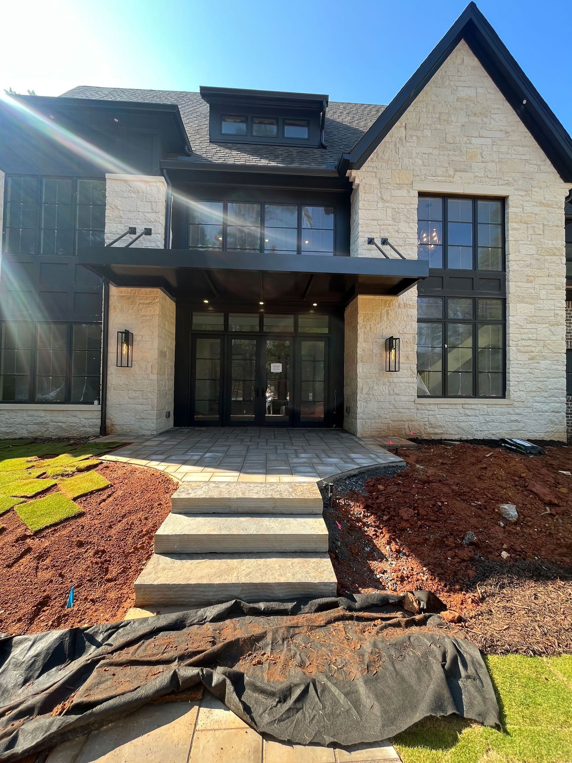 Stone facade house with black trim and entry, stone steps, mulch, and lawn.