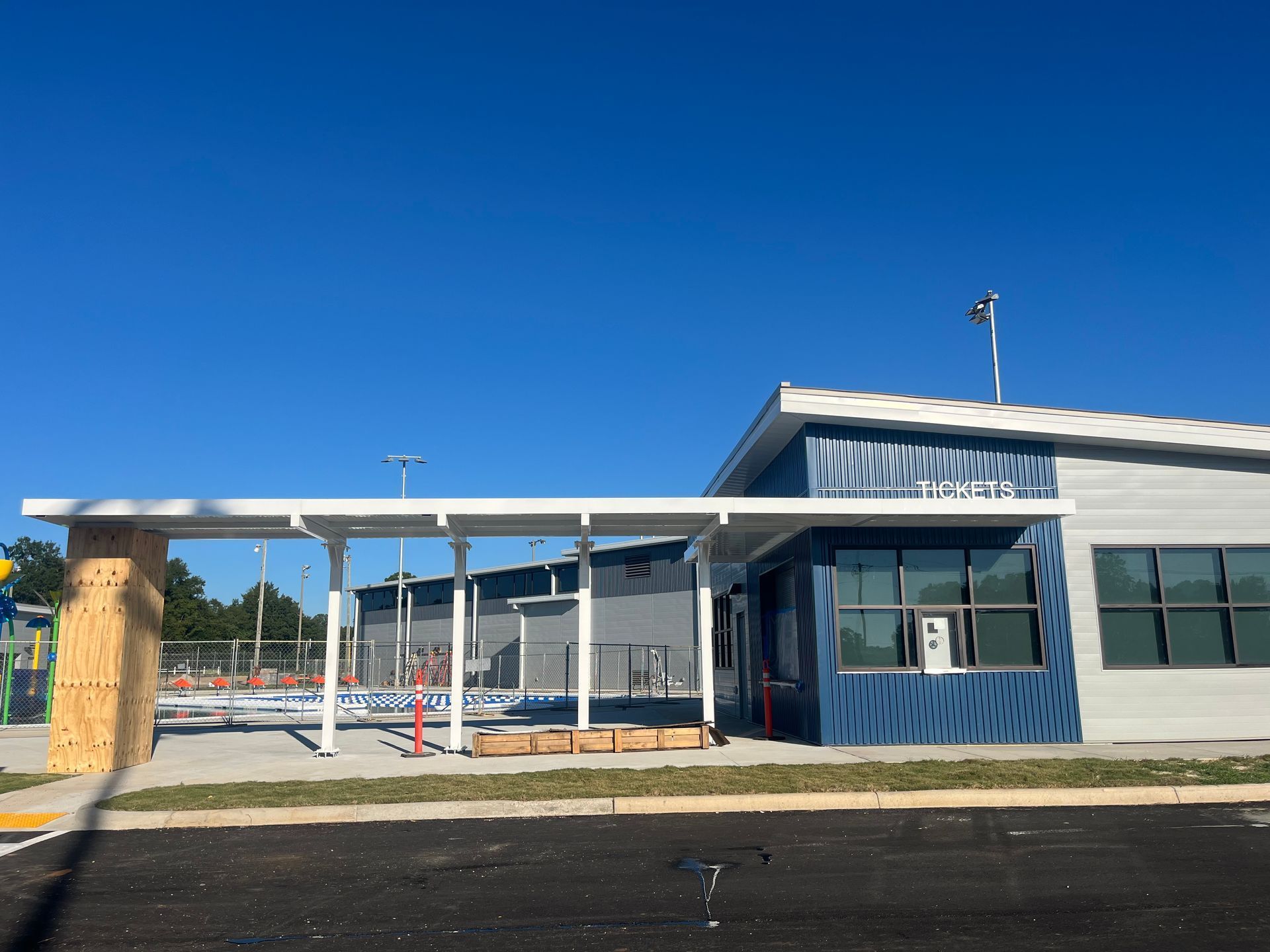 School building with a covered walkway and blue accents against a clear sky.