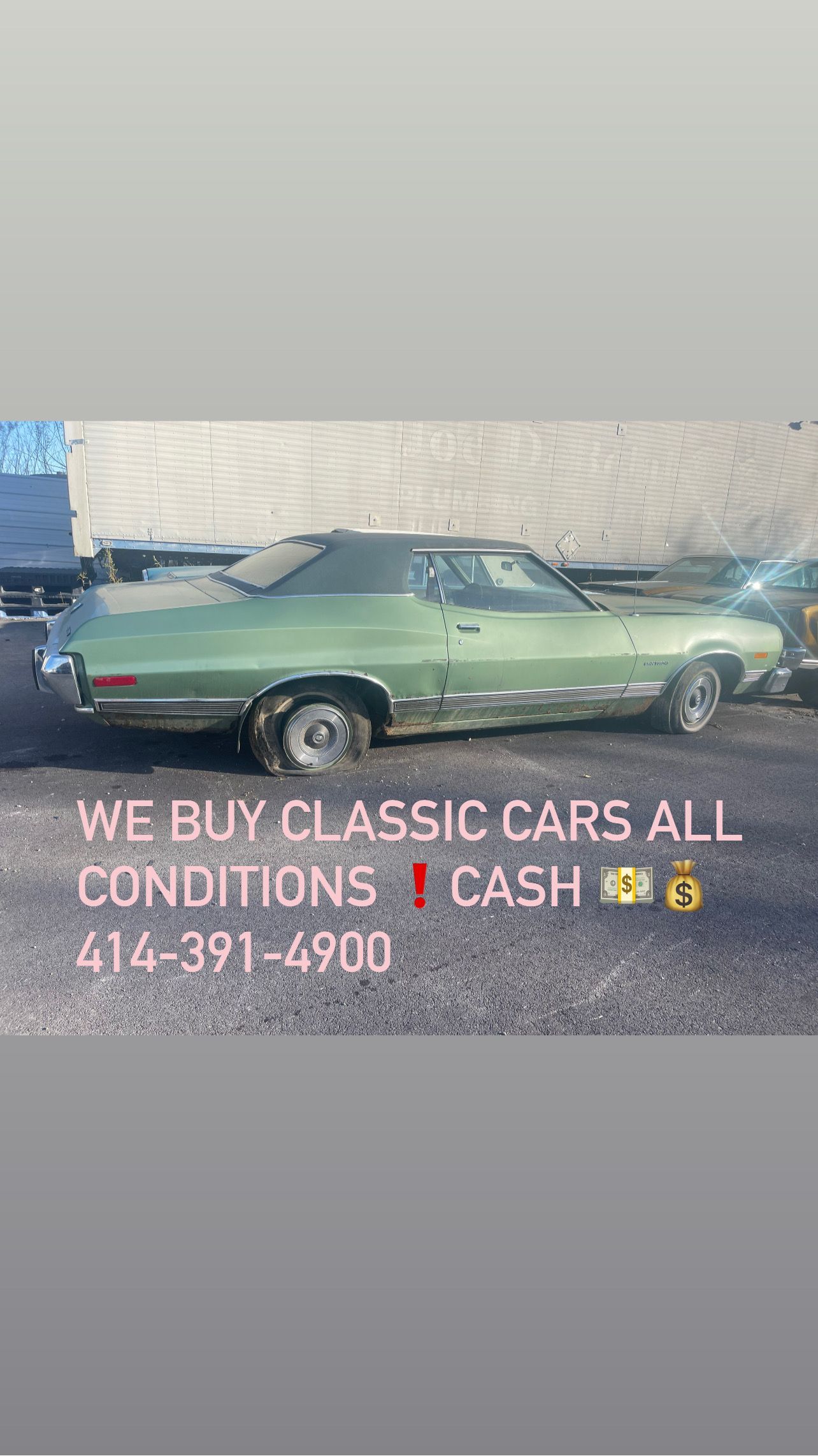 A green classic car is parked in a parking lot.