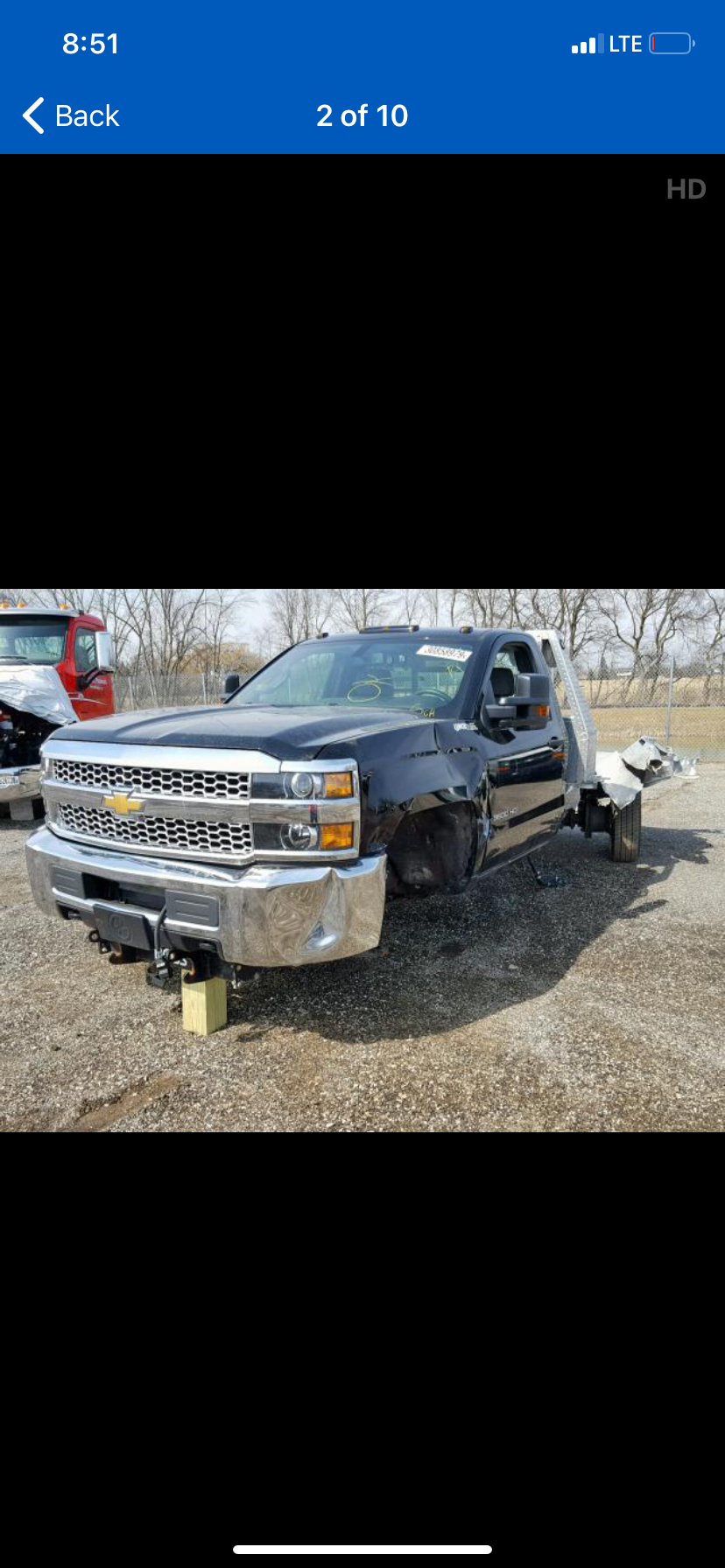 A gray truck is sitting on top of a dirt field.