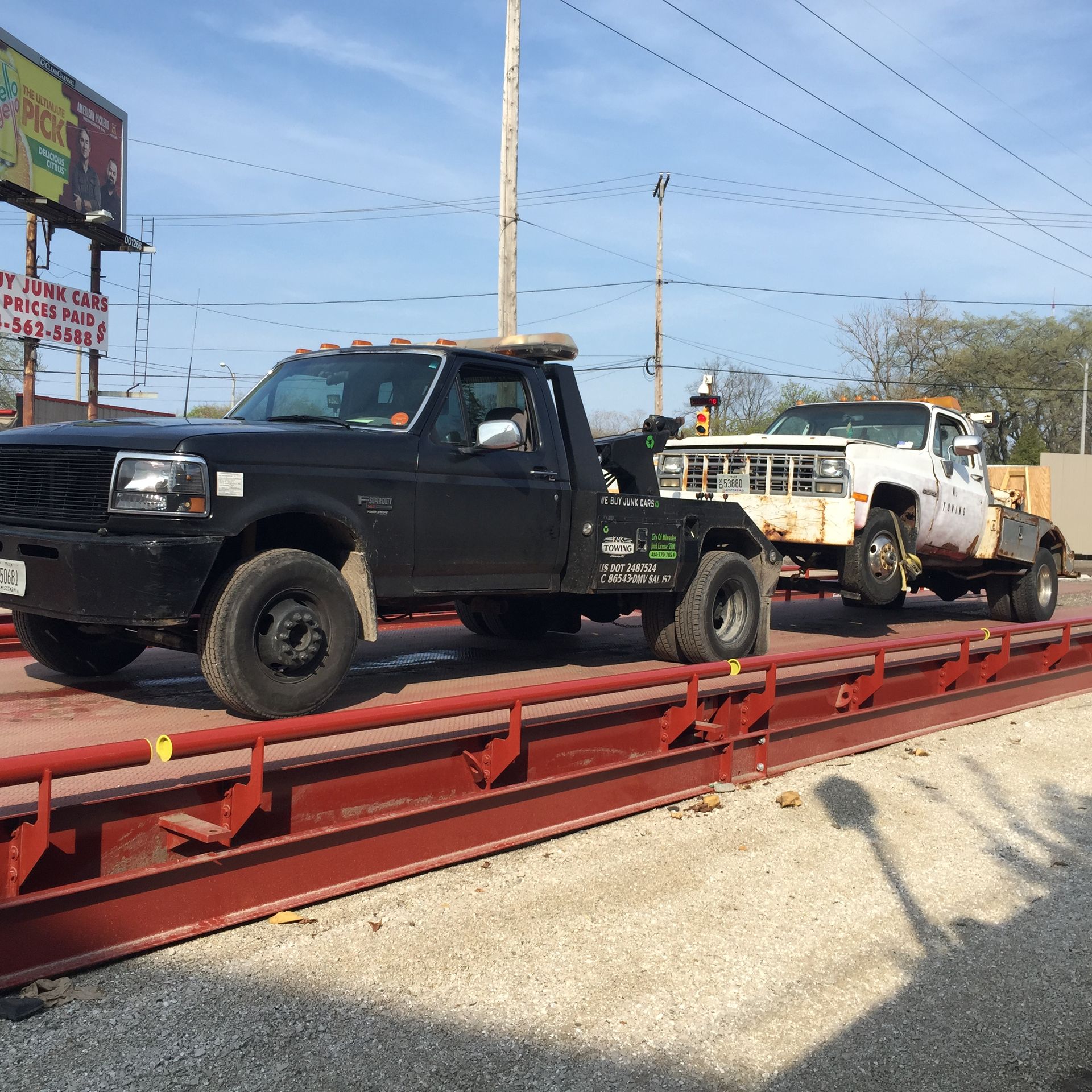 A tow truck is sitting on a scale next to another truck