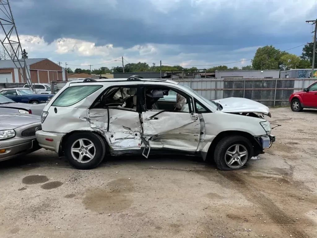 A white suv is sitting in a parking lot next to a red car.