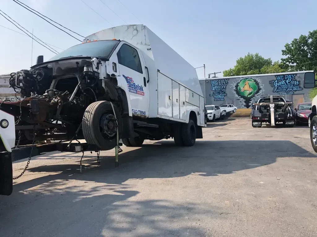 A truck is being towed by a tow truck in a parking lot.