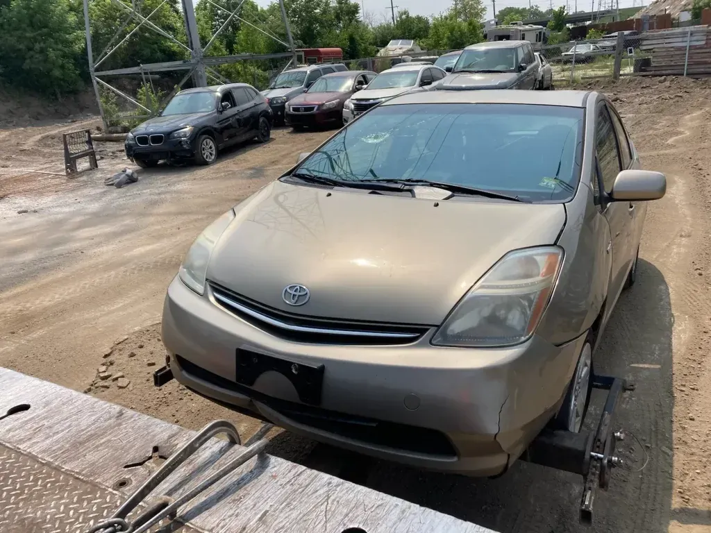 A toyota prius is parked in a lot with other cars.
