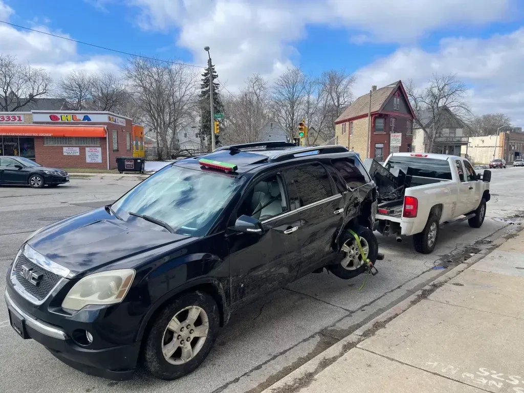A black suv is being towed by a white truck.
