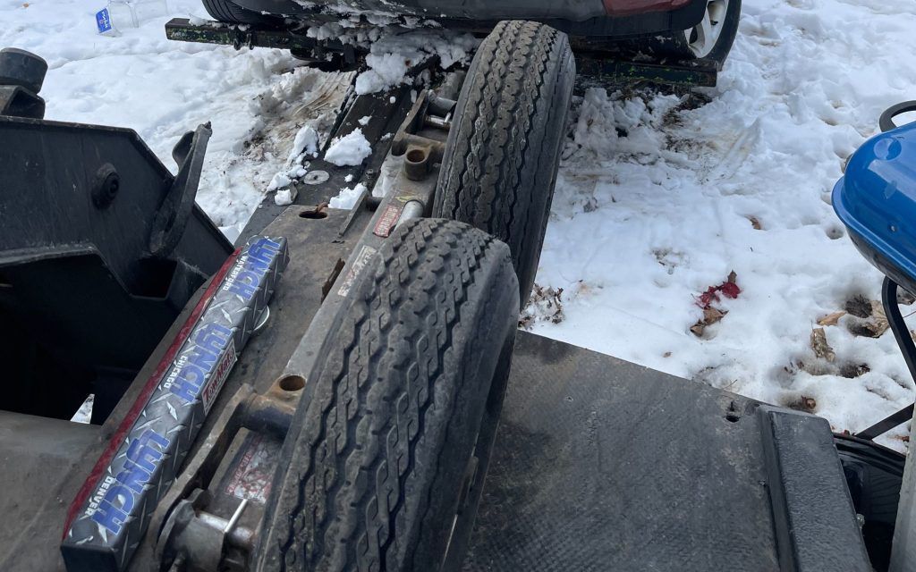 A car is being towed by a tow truck in the snow.