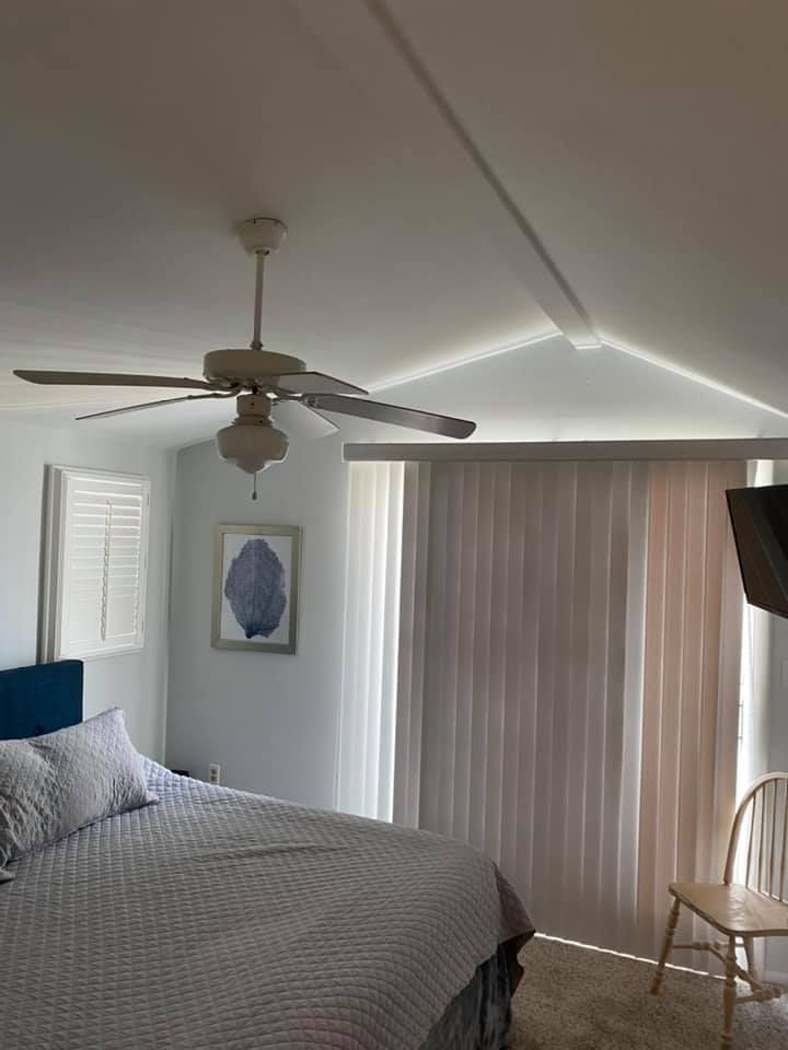 Bedroom with bed, ceiling fan, sliding doors, blinds, and a chair.